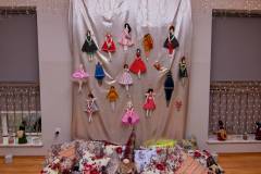 Zdjęcie przedstawia aranżację wystawy Uszyj zamiast kupować, wykonaną z uszytych lalek i poduszek dekoracyjnych i świątecznych,