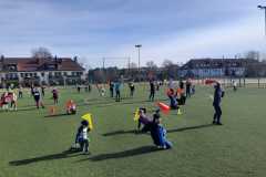 Impreza Pisankowo na sportowo  - Duża grupa dzieci na sztucznej murawie boiska Orlik, uczestniczące w zabawie z animatorem sportu.